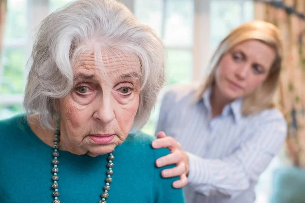 Смущенная старшая женщина с дочерью взрослого дома — стоковое фото