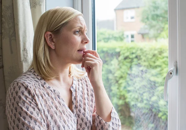 Mujer triste que sufre de agorafobia mirando por la ventana — Foto de Stock