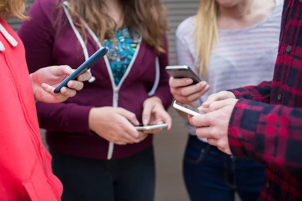 Grupul de adolescenți care împărtășesc mesaje text pe telefoanele mobile — Fotografie, imagine de stoc