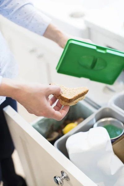 Cierre de la mujer poniendo residuos de alimentos en la papelera de reciclaje en la cocina — Foto de Stock