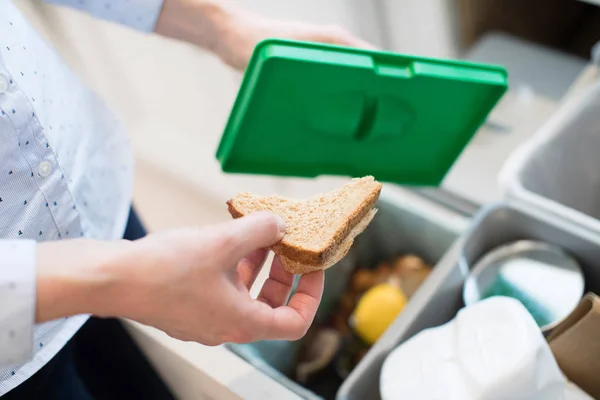 Близко женщина кладет пищевые отходы в мусорный бак на кухне — стоковое фото