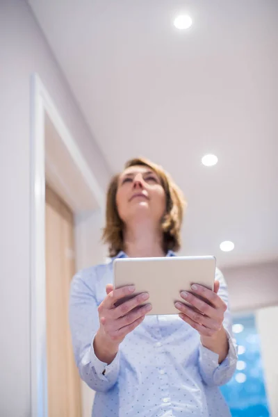 Mujer que controla la iluminación con la aplicación en la tableta digital — Foto de Stock