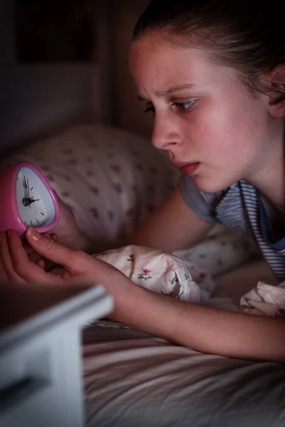 Menina ansiosa incapaz de dormir à noite olhando para o relógio — Fotografia de Stock