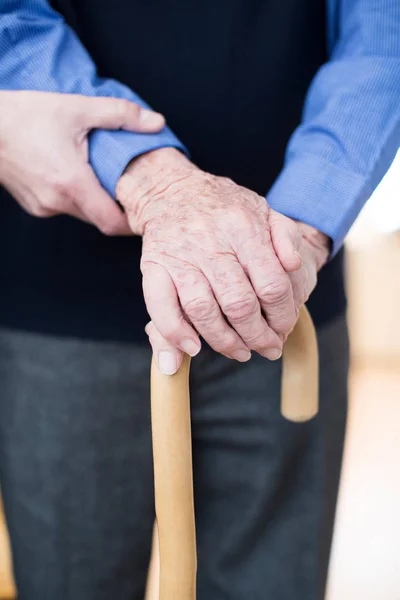 Руки старшого чоловіка на ходьбі палицею з працівника догляду в Backgrou — стокове фото