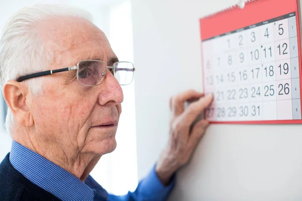 Hombre mayor confundido con demencia mirando el calendario de la pared — Foto de Stock