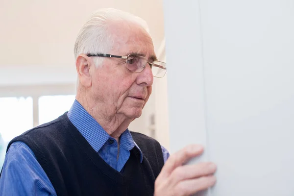 Forgetful Senior Man With Dementia Looking In Cupboard At Home — Stock Photo, Image