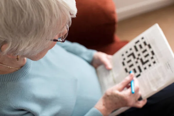 Mujer mayor haciendo crucigrama en casa — Foto de Stock