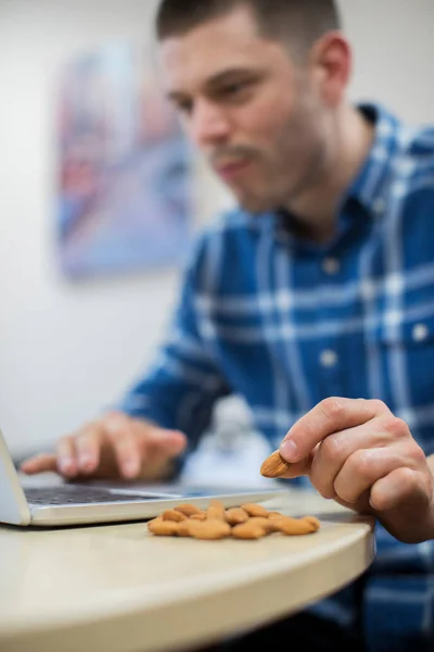 Trabajador masculino en la oficina teniendo bocadillo saludable de frutos secos — Foto de Stock