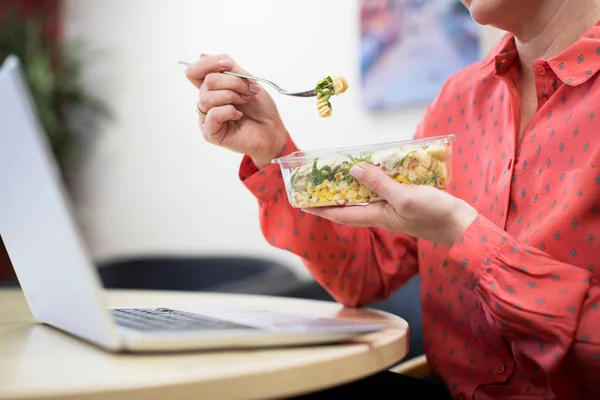 Женщина, работающая в офисе, обедает здоровой пастой за столом — стоковое фото