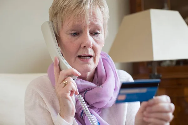 Äldre kvinna ger kreditkortsuppgifter på telefonen — Stockfoto