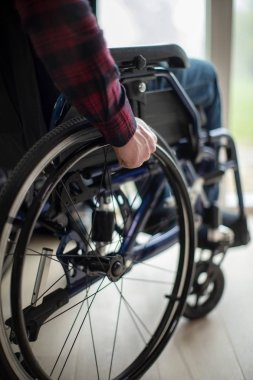 Evde pencere tarafından tekerlekli sandalyede oturan adam, yakın çekim