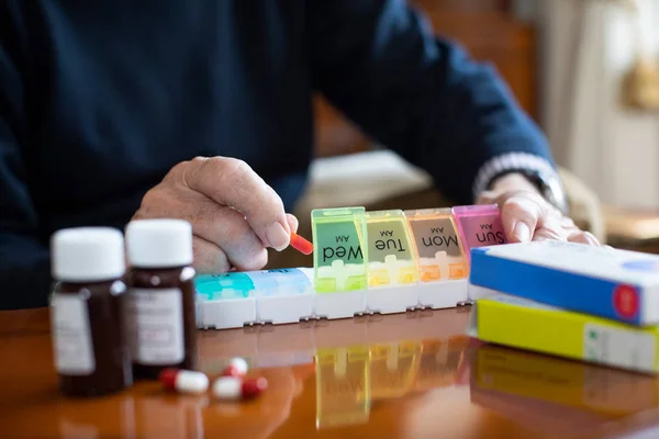 Primo piano di uomo anziano che organizza farmaci in pillola dispenser — Foto Stock