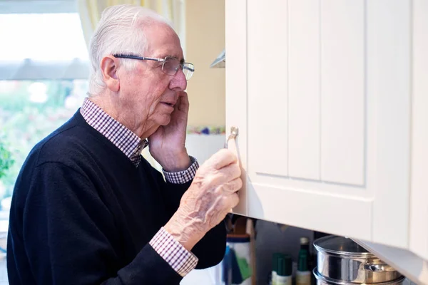 Забывчивый пожилой человек со слабоумием, заглядывающий в шкаф дома — стоковое фото