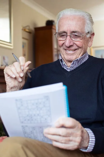 Ανώτερος άνθρωπος κάνει Sudoku παζλ στο σπίτι — Φωτογραφία Αρχείου