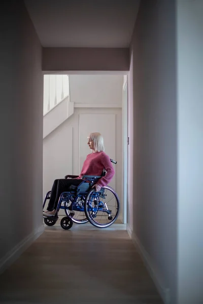 Vrouw zit in een rolstoel thuis in de hal — Stockfoto