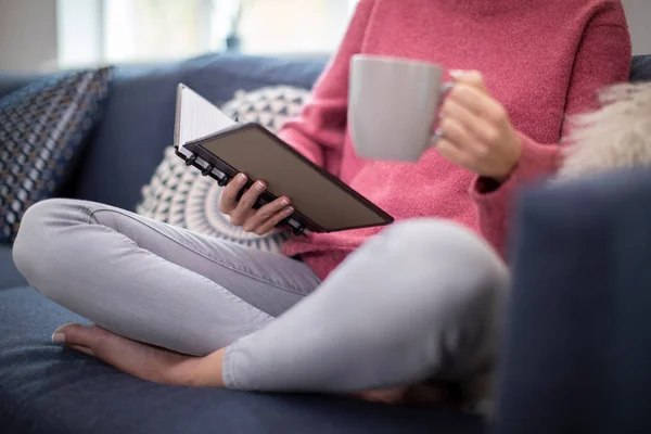 Primer plano de la mujer con la bebida caliente que relaja en el sofá en el hogar Readin — Foto de Stock