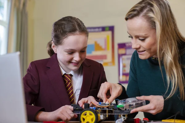 Teacher Helping Female Pupil Wearing Uniform To Build Robot Car — 스톡 사진