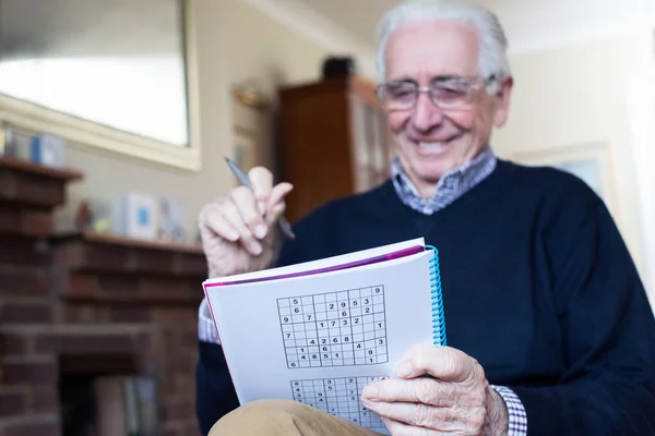 Starszy mężczyzna robi Sudoku Puzzle w domu — Zdjęcie stockowe