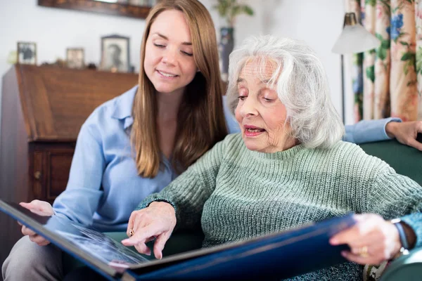 Großmutter schaut mit erwachsener Enkelin auf Fotoalbum — Stockfoto