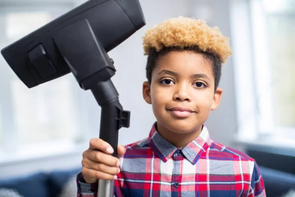 Portrait Of Boy Helping Out With Chores At Home Holding Vacuum Cleaner