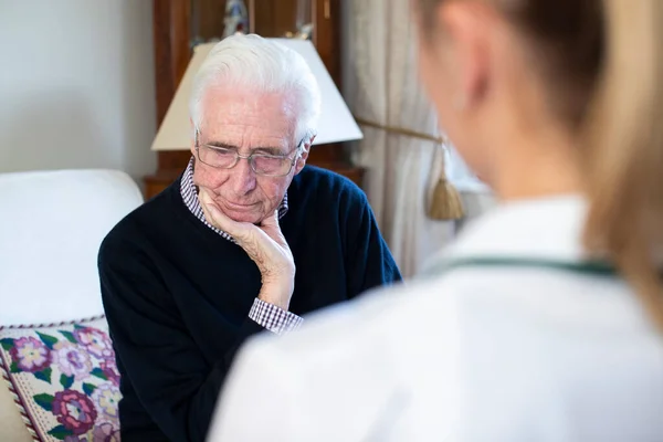 Nieszczęśliwy Starszy Mężczyzna Odwiedzany Przez Pielęgniarkę — Zdjęcie stockowe