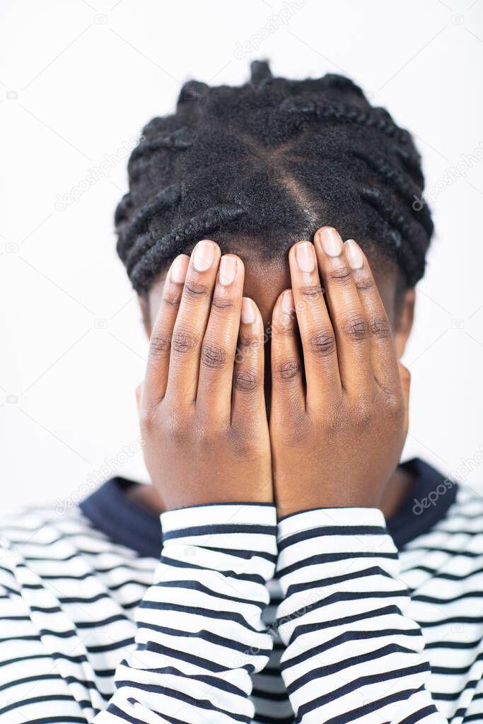 Unhappy Teenage Girl Covering Face With Hands Against White Background