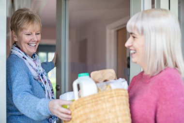 Kadın komşu Coronavirus sırasında kendini tecrit ederken yaşlı kadına alışverişte yardım ediyor.
