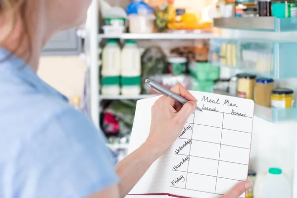 Frau Steht Mit Notizbuch Vor Kühlschrank Küche Und Schreibt Wöchentlichen — Stockfoto