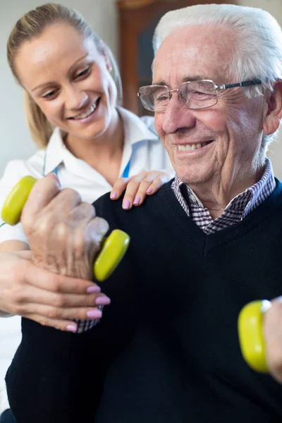 Vrouwelijke Fysiotherapeut Helpt Oudere Man Thuis Gewichten Tillen — Stockfoto