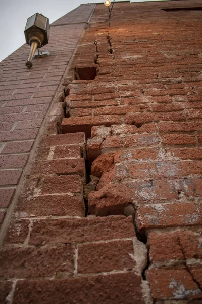 벽돌 외벽을 쌓아 올린 오래 된 시내 건물 위를 달리고 있는 거대 한 균열 W — 스톡 사진