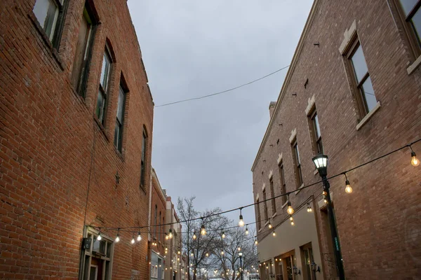 Lights strung between two old downtown buildings and an overcast — Stock Photo, Image