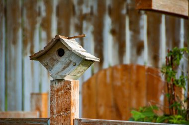 Küçük elmas şekilli kuş evi bir çit direğinde dinleniyor.