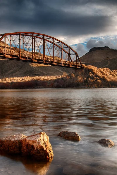 Largo puente oxidado mirando desde el borde del agua — Foto de Stock