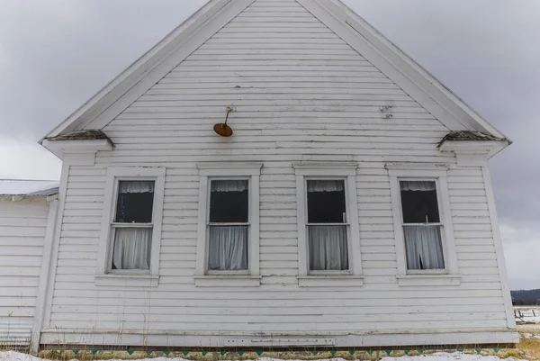 Vier drapierte Fenster hinter einem alten weißen Schulhaus in Idaho — Stockfoto