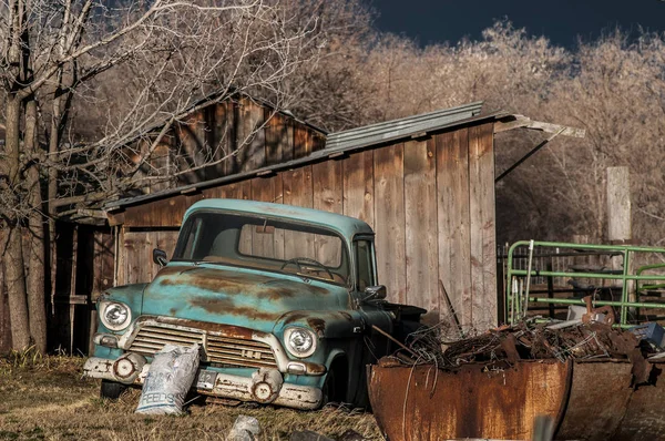 Antique warm front lit rusty light blue pickup truck sits near a