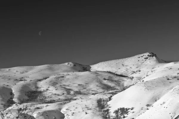 Černobílý obraz vysoké pouštní kopce pokryté sněhem a moo — Stock fotografie