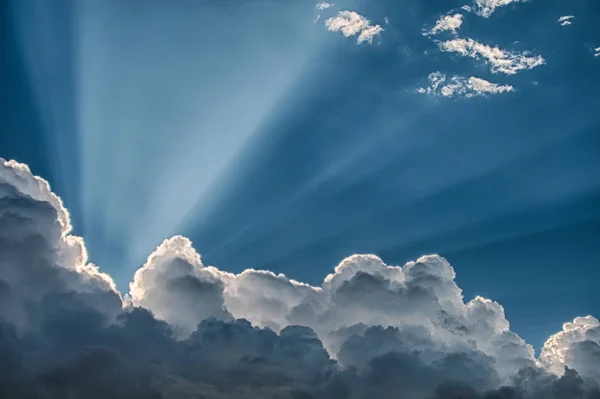 Sunbeams shinning upward from the setting sun over the billowy b — Stock Photo, Image