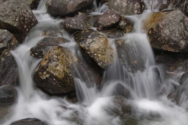 Cachoeira que flui sobre rochas castanhas envelhecidas e musgosas com a motio — Fotografia de Stock