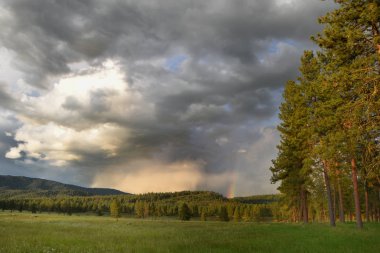Distant Rainbow in the Breaking Clouds