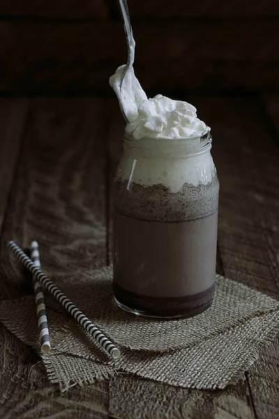 cookies and cream milkshake in a glass jug on wooden background