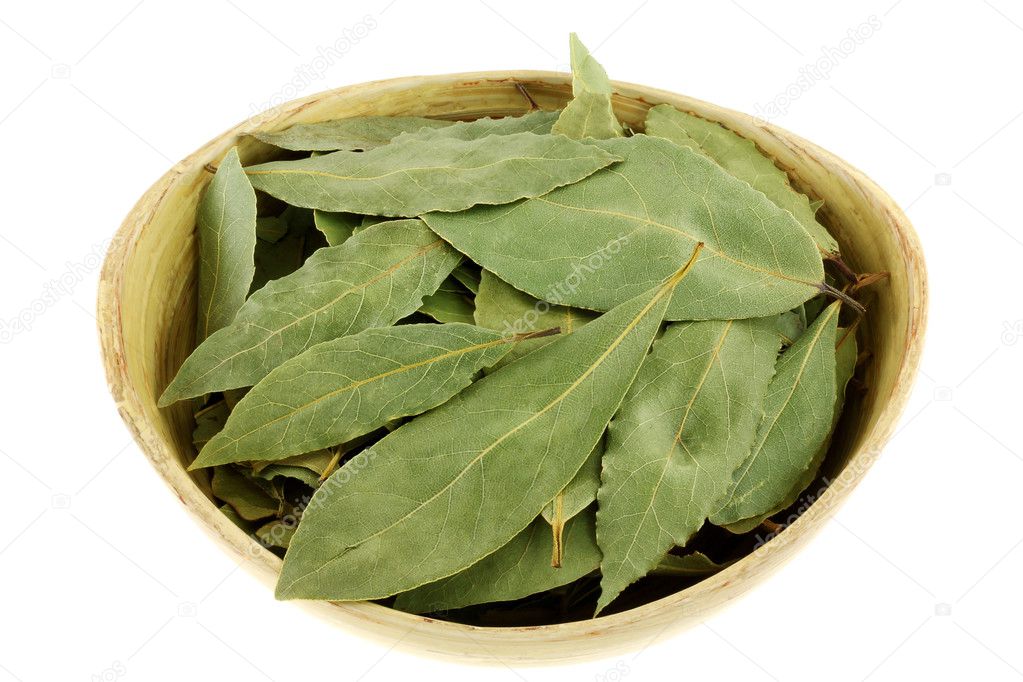 Dried Bay leaves in a wooden bowl isolated on white background