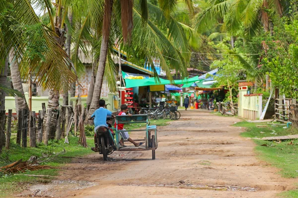 Young kids driving tricycle motorcycle on unpaved street in Champasak Province, Laos — 图库照片