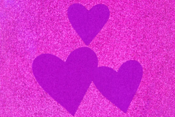 Glittery texture of glitter in magenta with blurred purple violet hearts — Stock Photo, Image