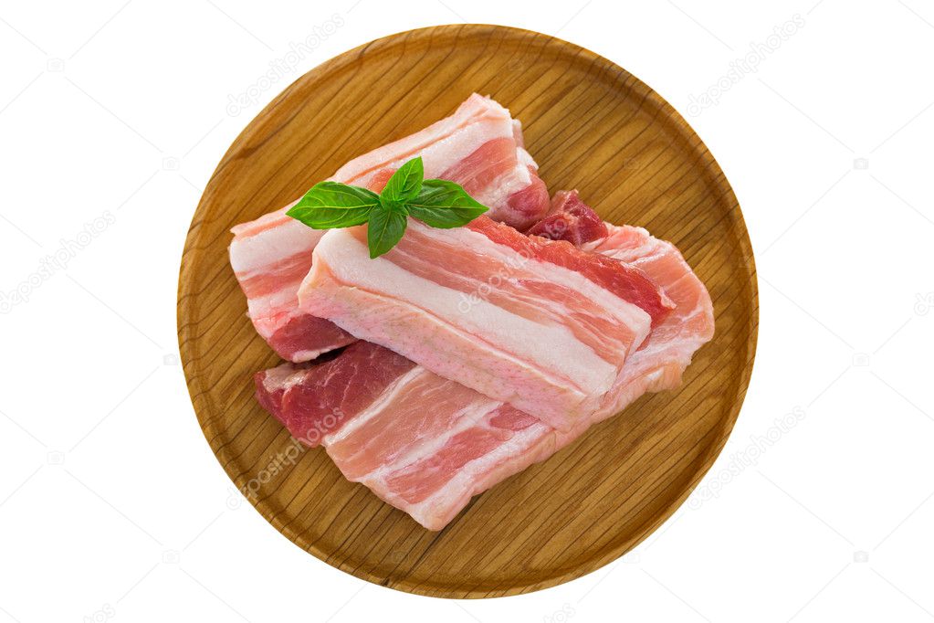 Slices of raw fresh pork belly cut on wooden plate isolated on white