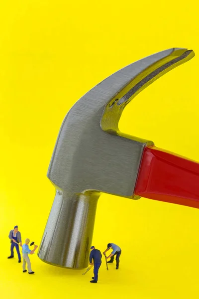 Steel claw hammer on yellow background with small mini miniature