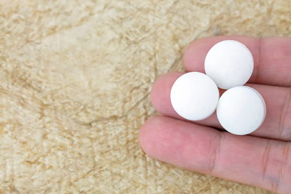 Vue du dessus de 3 médicaments blancs sur les doigts avec du papier de mûrier brun — Photo