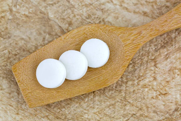 3 fehér gyógyszerek a fakanállal barna eperfa papír háttér — Stock Fotó