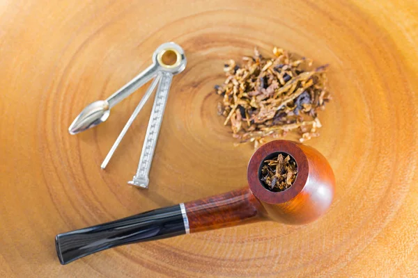 Classic blended aromatic pipe tobacco next to tool to pick ream tamper tobacco