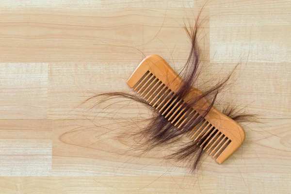 Hair on wooden comb on wooden floor with copyspace.