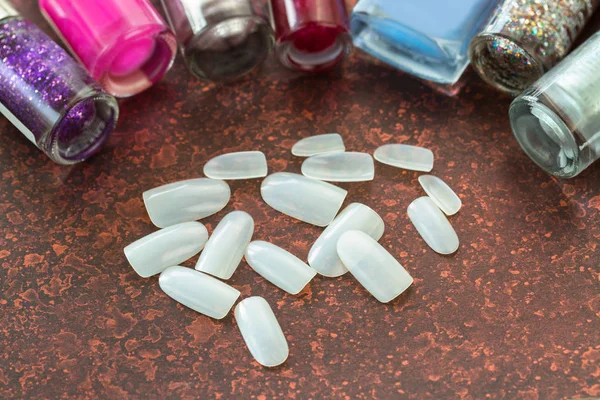 Kunstmatige plastische nail in de buurt van flessen van nagellak vernis lak — Stockfoto